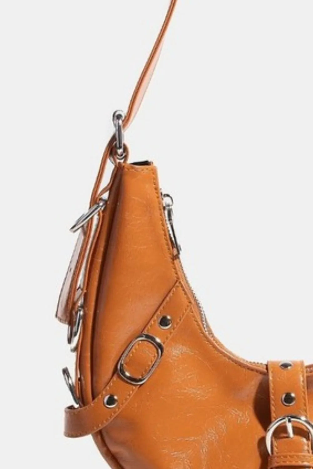 Cognac brown crescent leather shoulder bag with metal buckles and tassels.