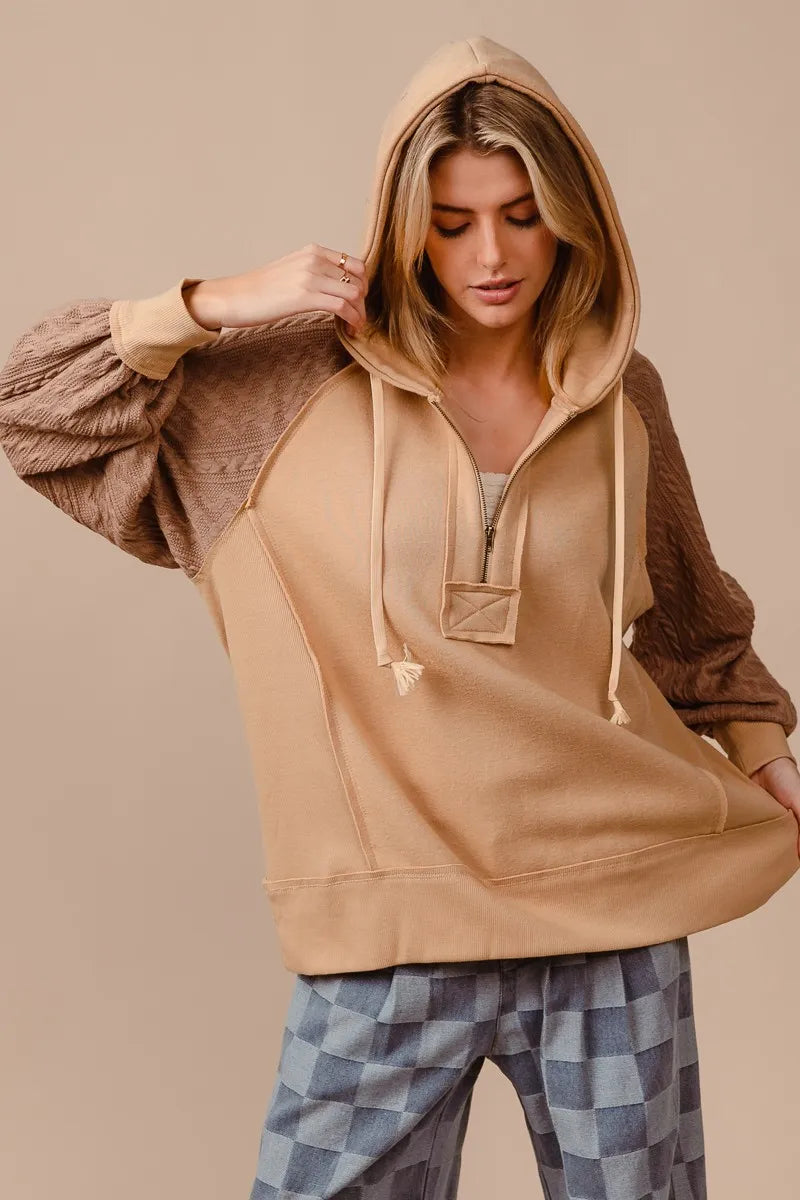 BiBi half zip French terry hoodie in beige with knit sleeves, modeled on a woman.