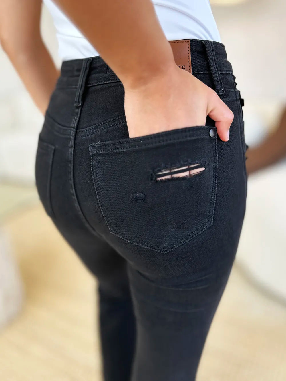 Rear view of Judy Blue high-waist distressed flare jeans on a model, showing black wash and pocket details.