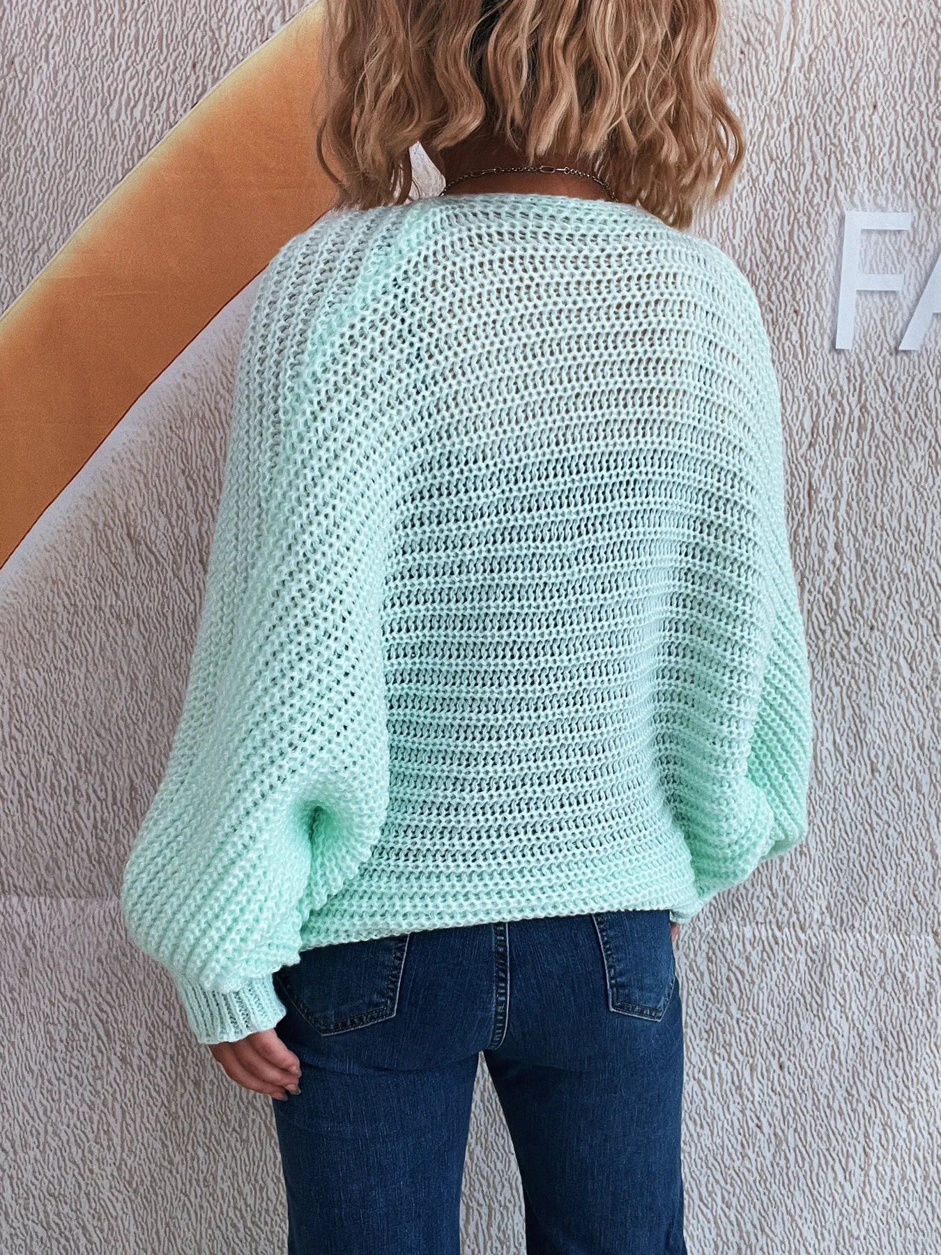 Rear view of light blue tie front long sleeve cardigan on model with jeans.