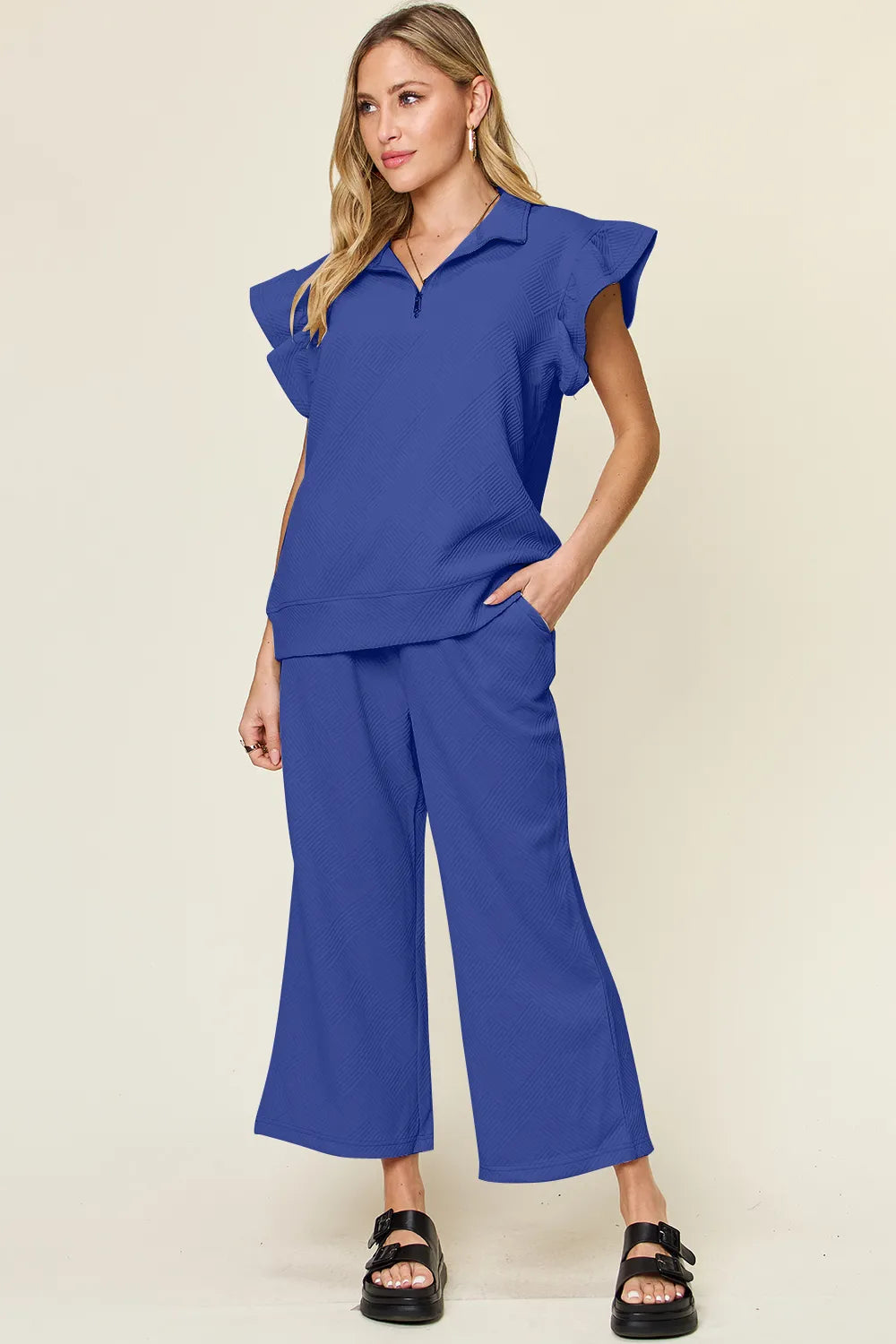 Woman modeling a textured ruffle short sleeve top and wide leg pants set in blue.