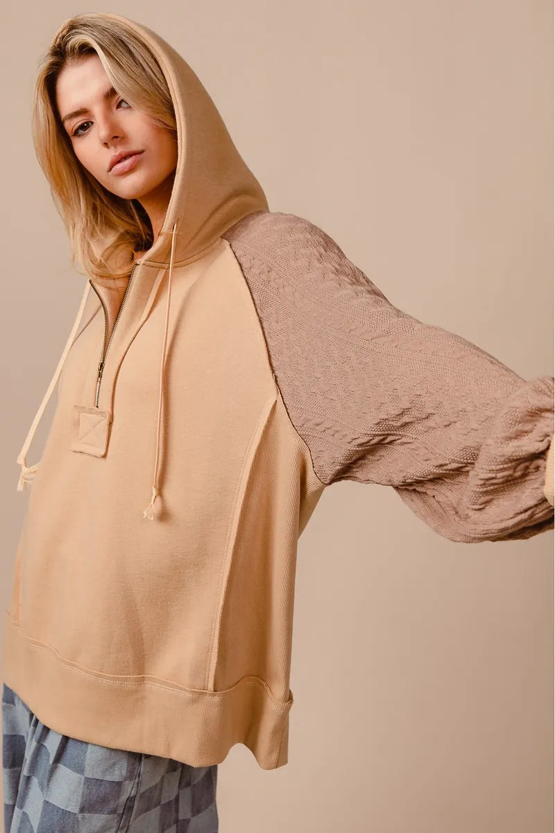 BiBi half zip French terry hoodie in beige with knit sleeves, modeled on a woman.