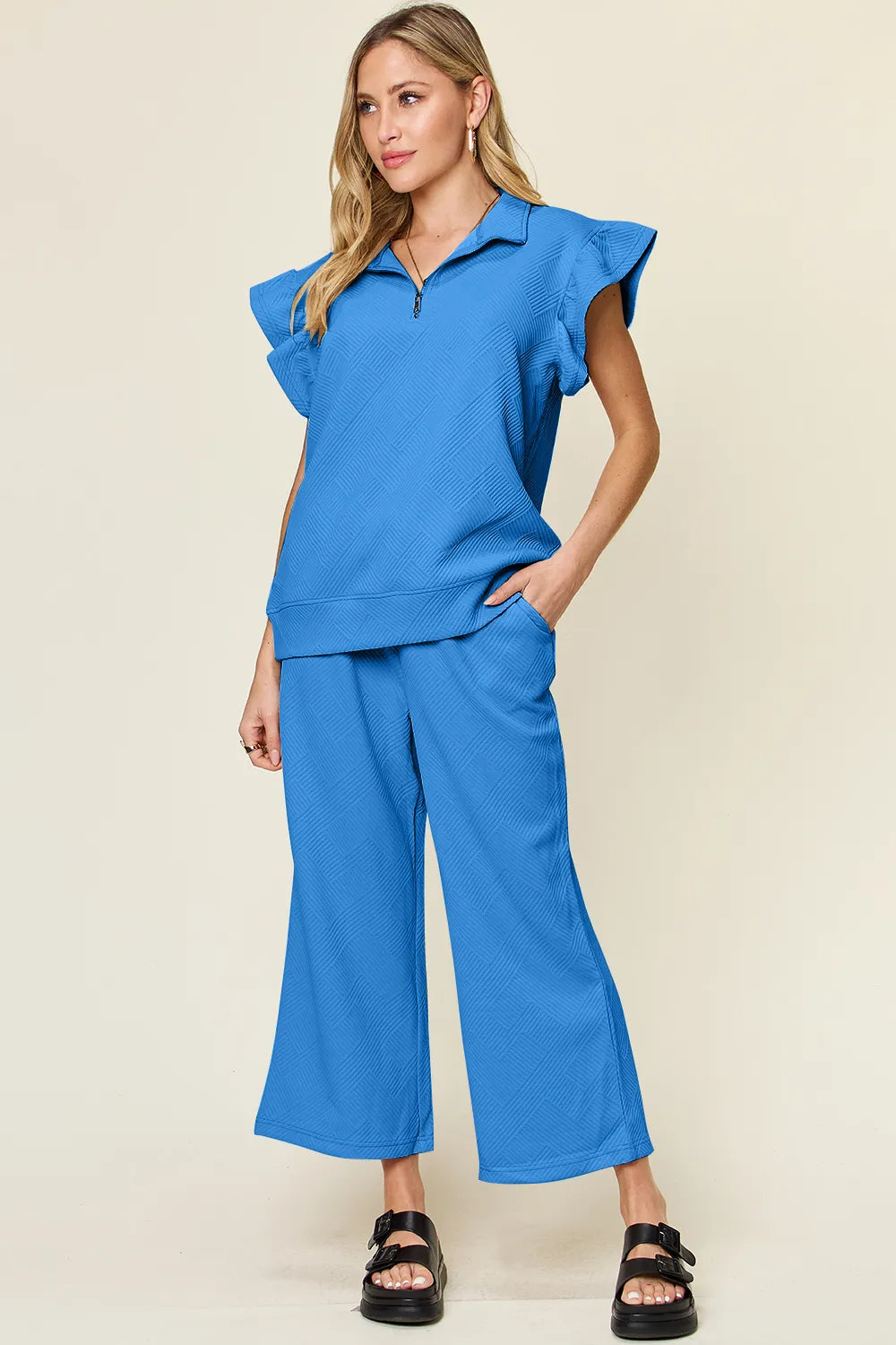 Woman modeling a textured ruffle short sleeve top and wide leg pants set in blue.