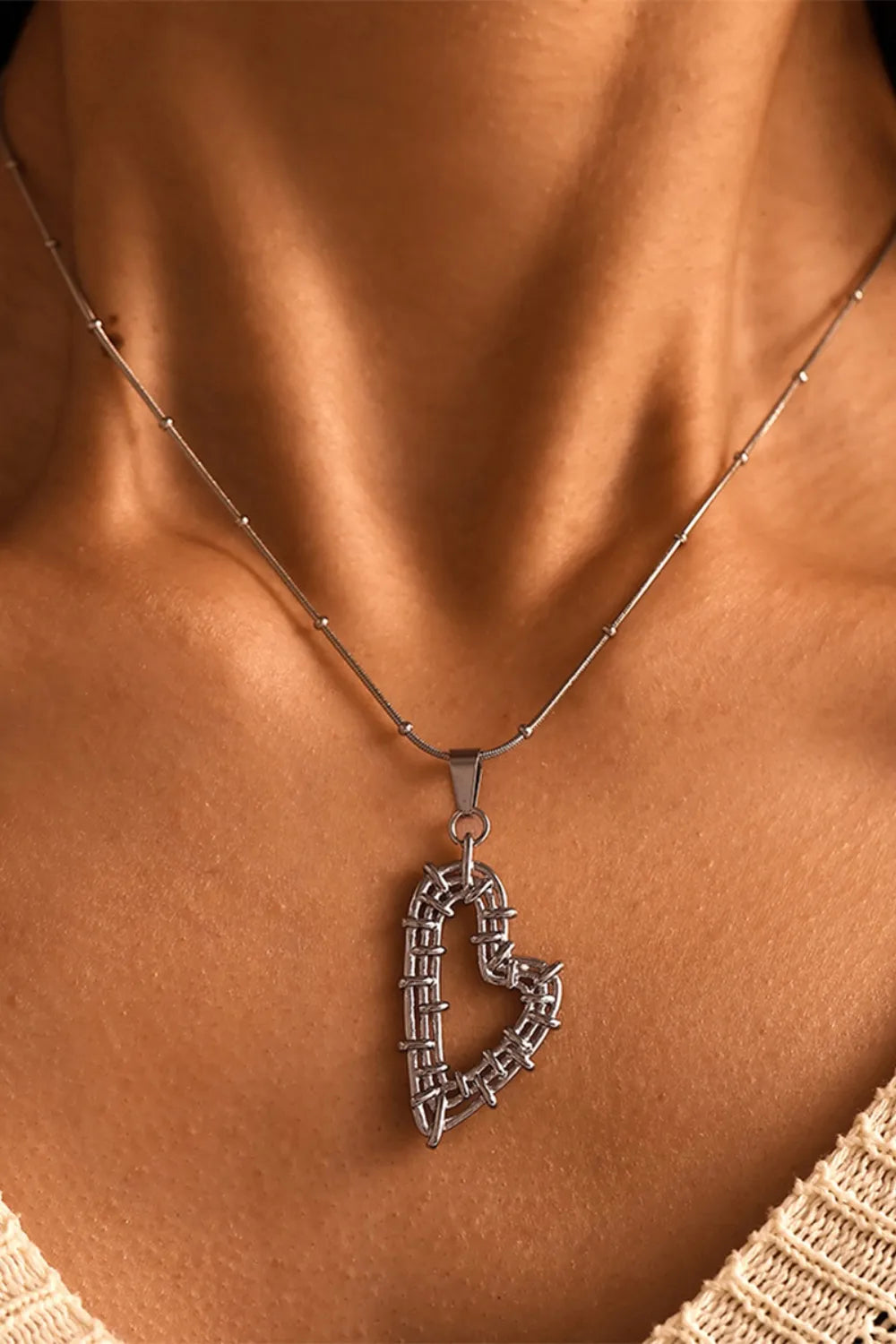 A woman wearing a gold-plated stainless steel necklace with a textured heart pendant.