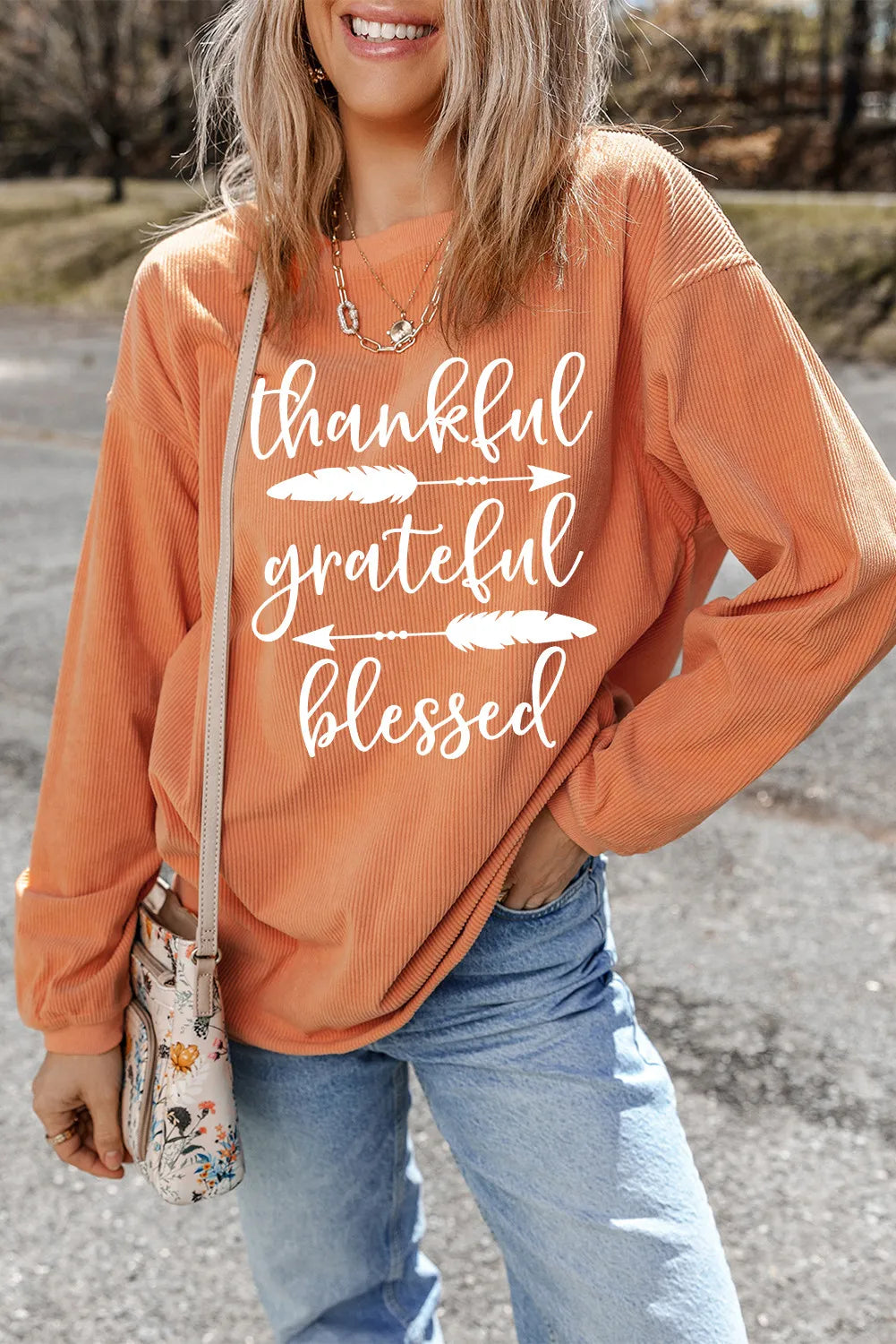 Orange long-sleeve polyester sweatshirt with "Thankful Grateful Blessed" graphic in white letters and arrows.