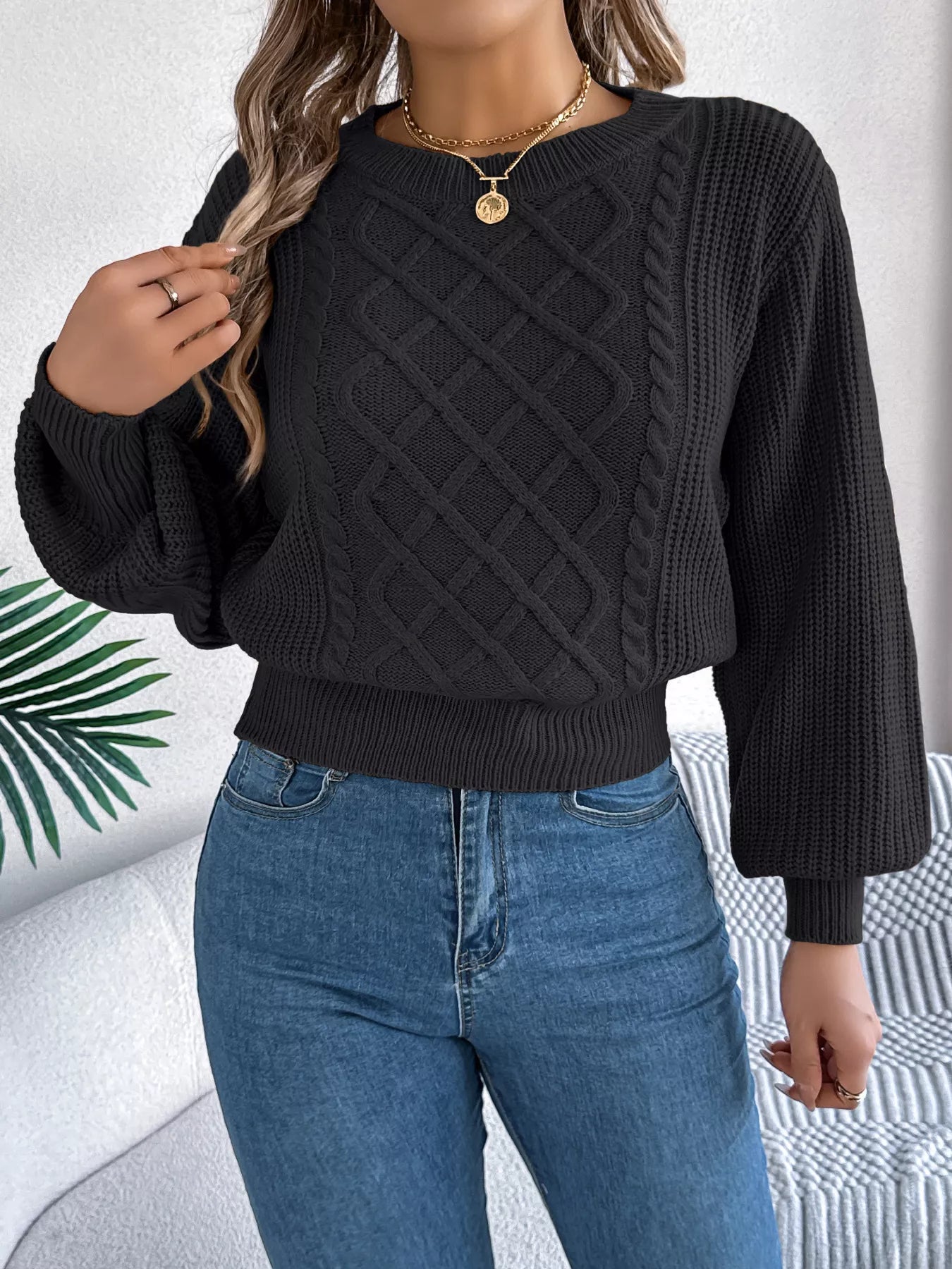 Long sleeve acrylic sweater with cable knit diamond pattern in neutral color.