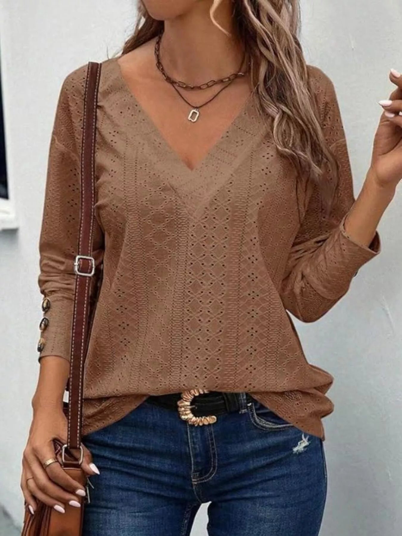 Long sleeve eyelet v-neck blouse in a polyester blend with decorative buttons.