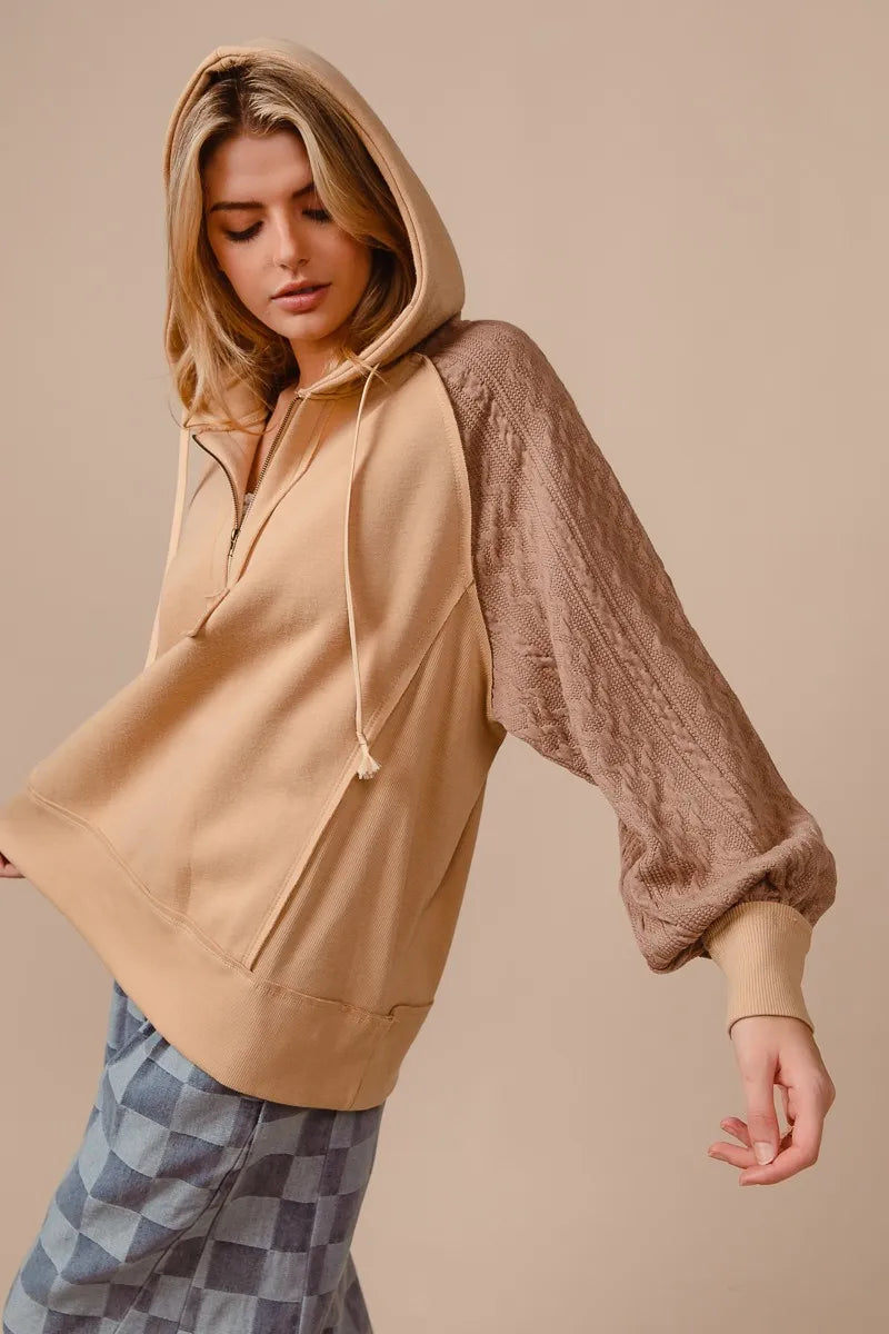 Beige half-zip French terry hoodie with knit sleeves on a model.
