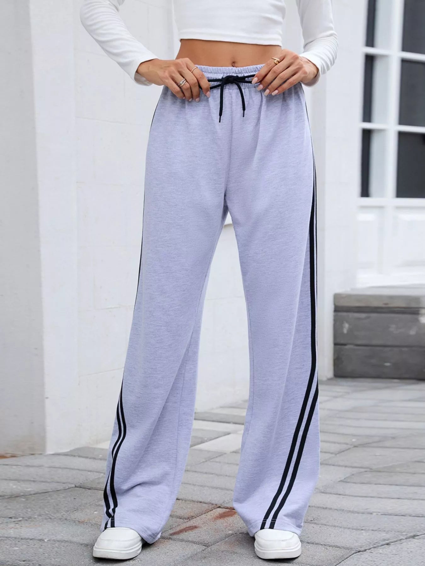 Gray rayon blend wide-leg pants with black side stripes and drawstring waist, modeled on a woman.
