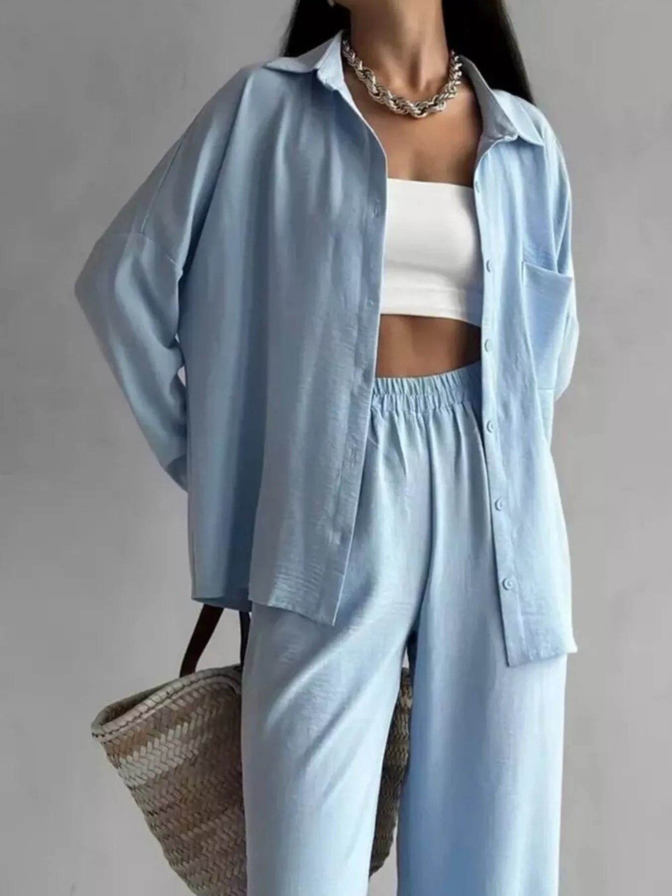 Woman wearing a light blue button-down shirt and matching wide-leg pants set with slight stretch.
