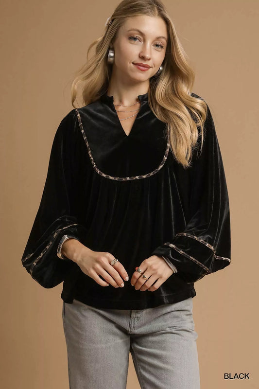 Black velvet long-sleeve blouse with contrast trim on a model.