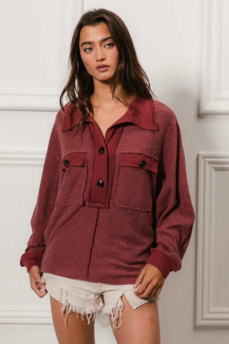 Oversized maroon French terry collared top with buttons and pockets, modeled on a woman.