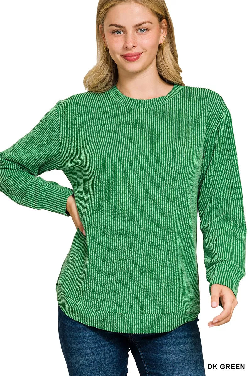 A plus size woman models a dark green raised rib round neck long sleeve top.