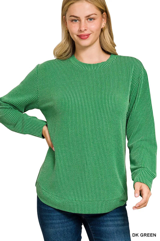 A plus size woman models a dark green raised rib round neck long sleeve top.