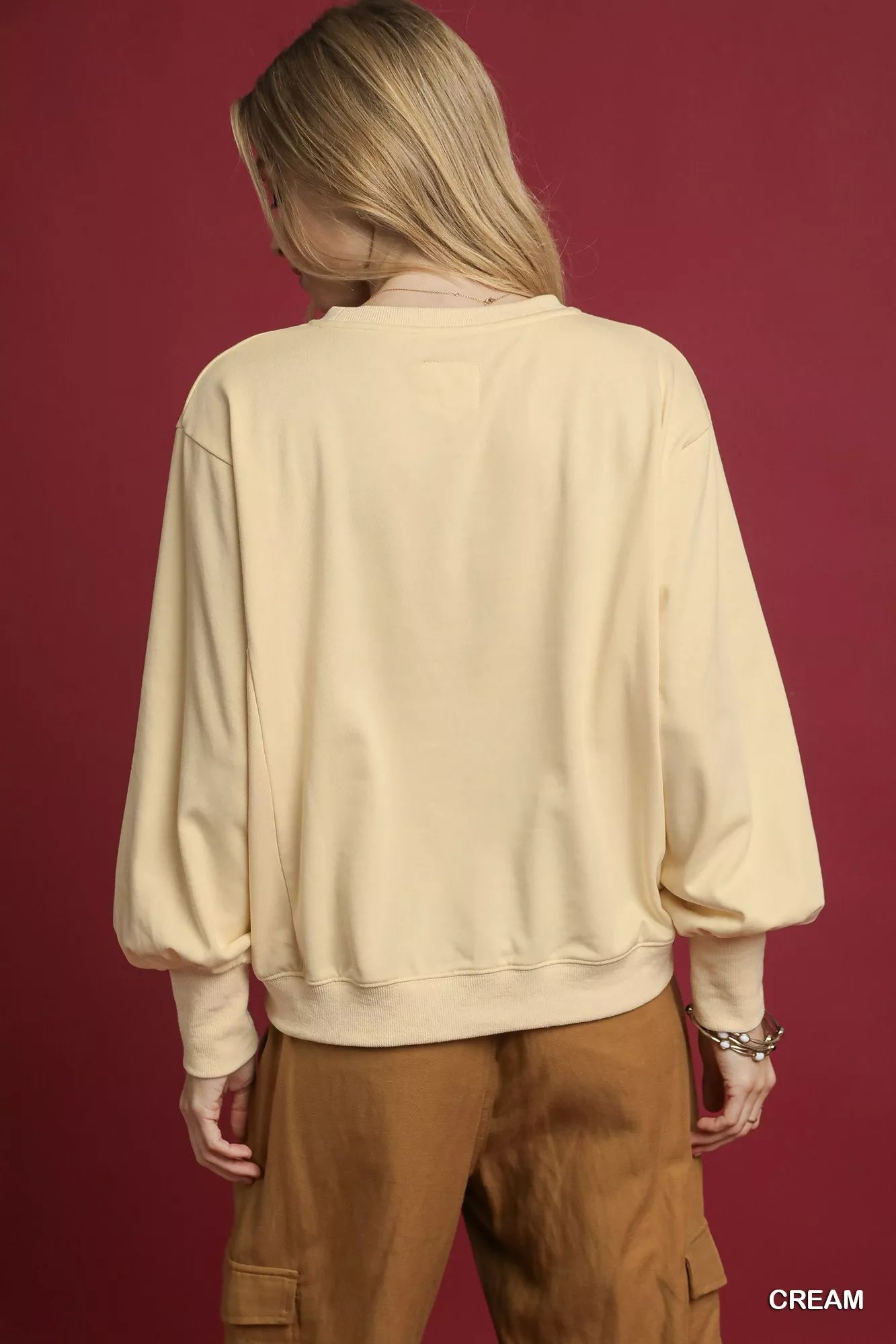 Rear view of cream French terry sweatshirt with applique details on a model.
