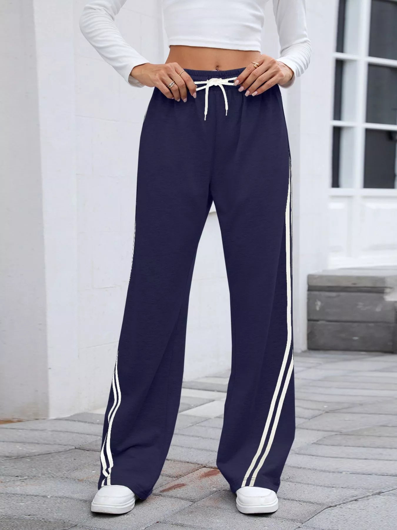 Model poses in navy side-striped wide-leg pants with drawstring waist.
