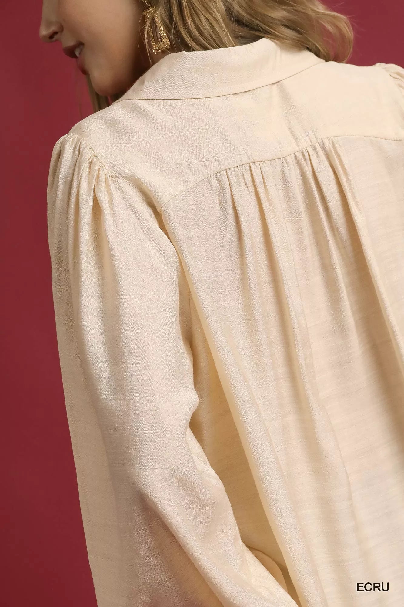 Rear view of cream long sleeve blouse with subtle pleats and leopard print trim.