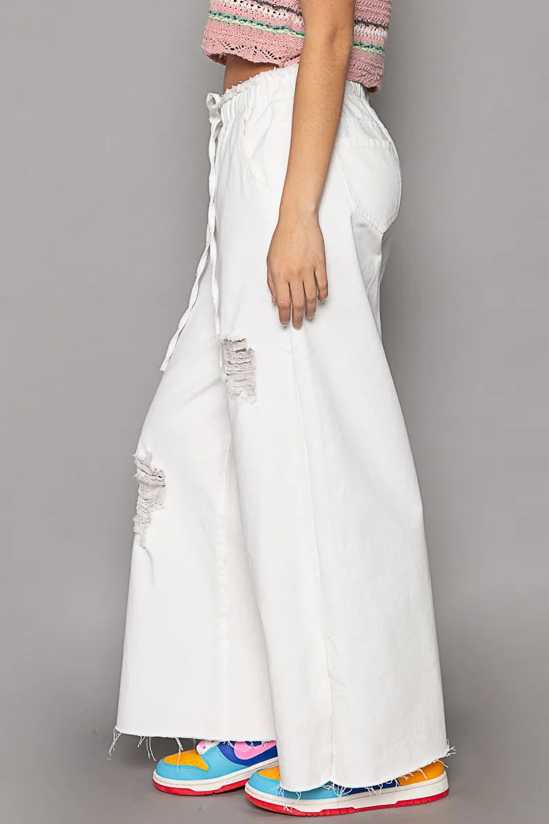 White distressed drawstring wide-leg cotton pants on a model with sneakers.