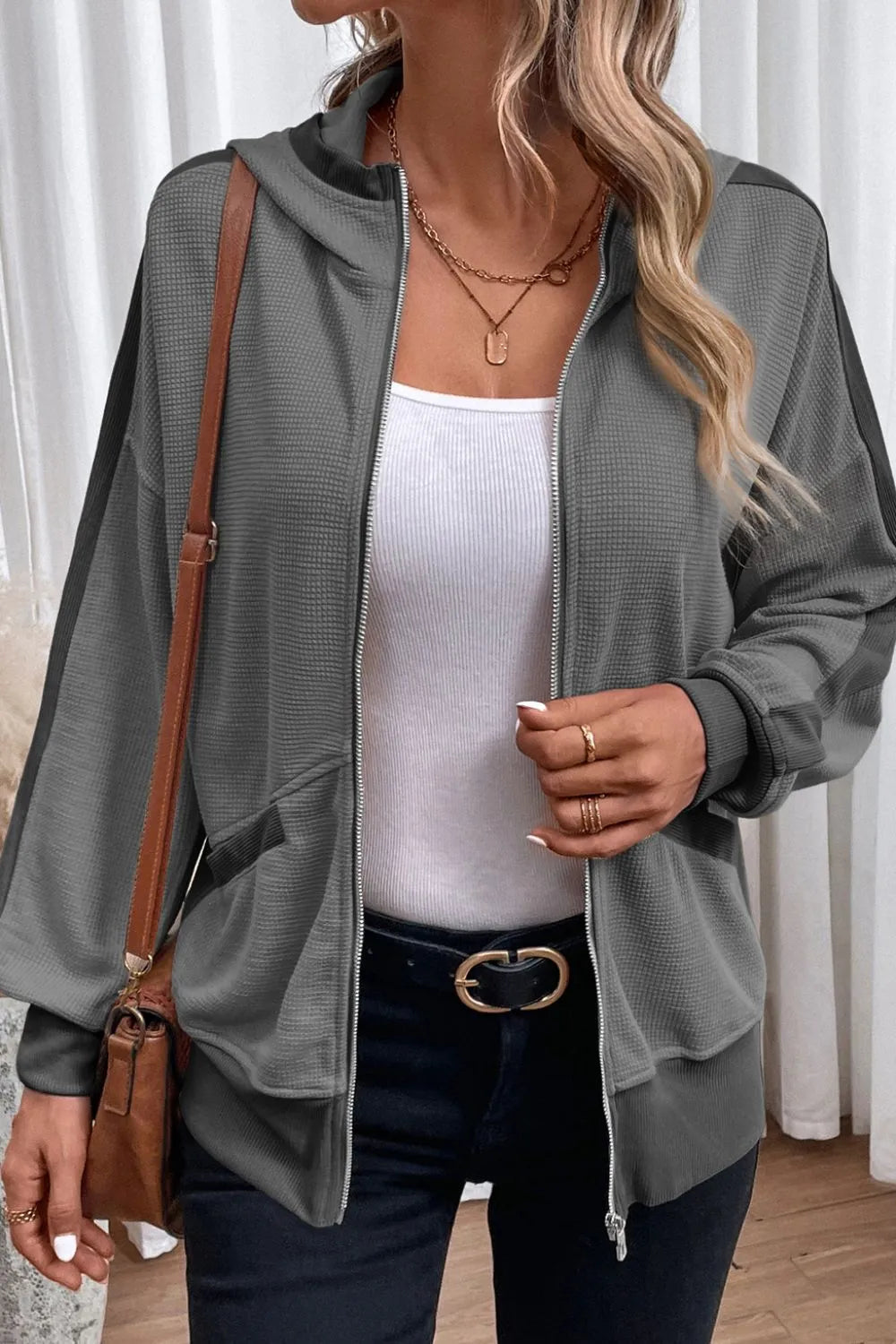Woman wearing a soft pink waffle-knit zip-up hooded jacket with pockets.
