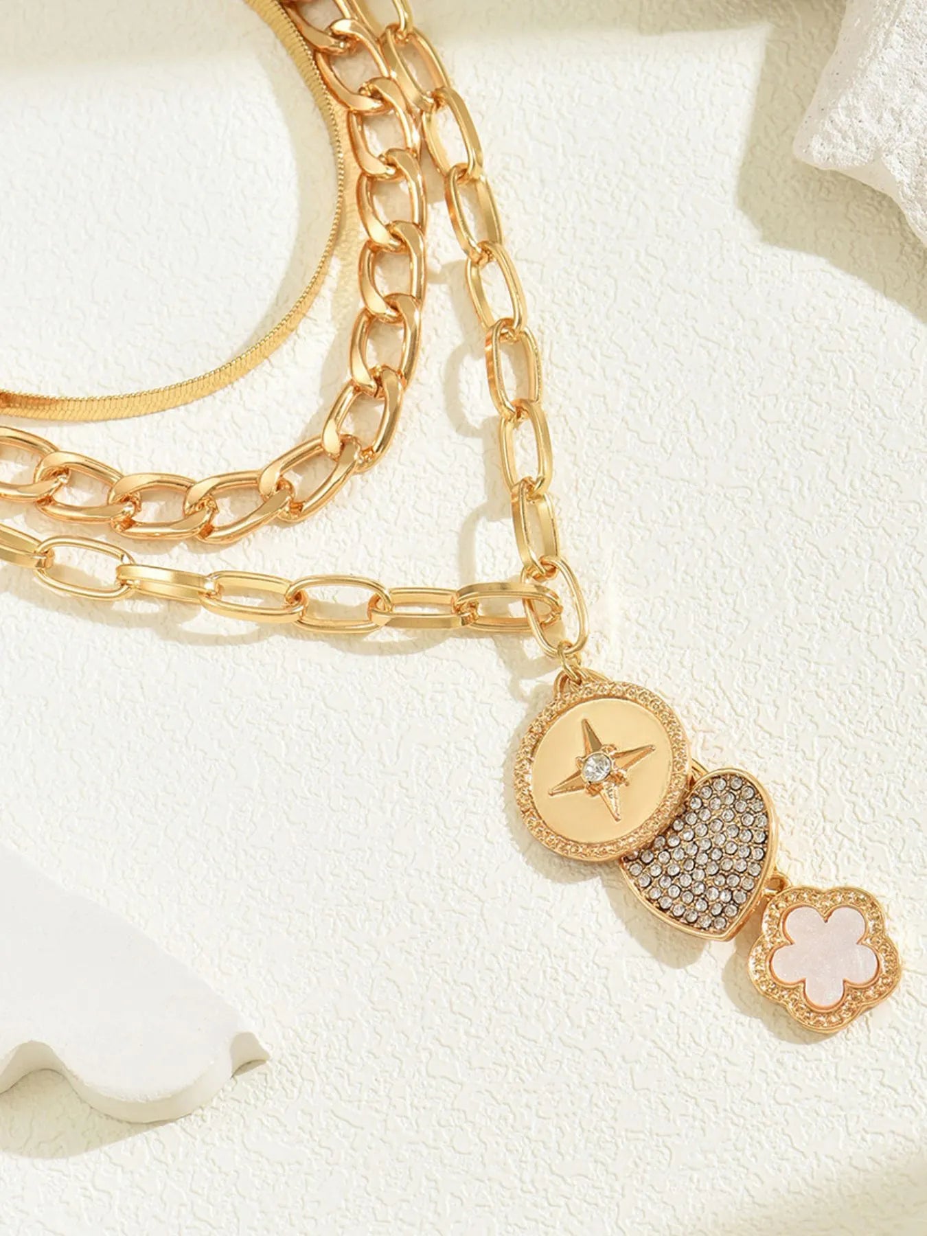 Layered gold-plated stainless steel necklace with star and flower pendants.