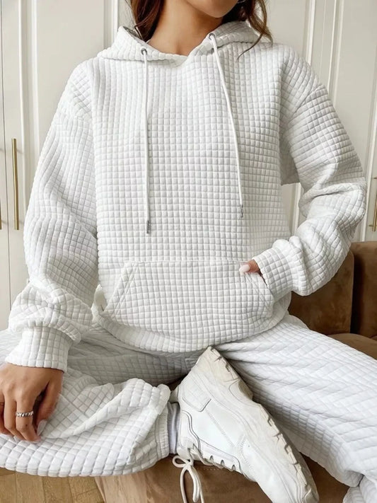 White waffle knit hoodie with drawstring hood and front pocket, modeled on a seated woman.