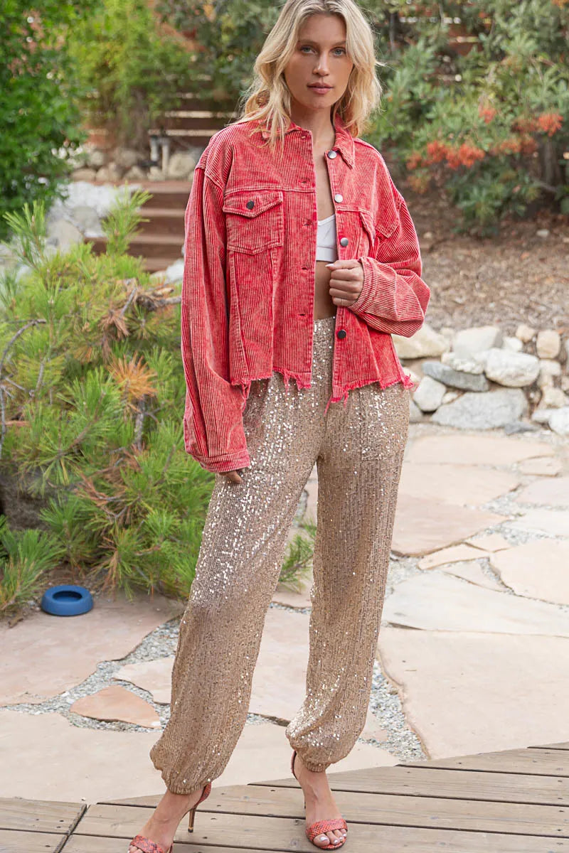 Woman wearing a red corduroy button-down trucker jacket with chest pockets.