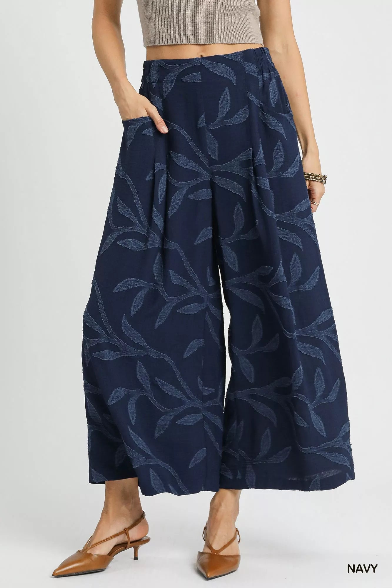 Navy jacquard wide-leg pants with leaf pattern and side pockets, modeled on a woman.