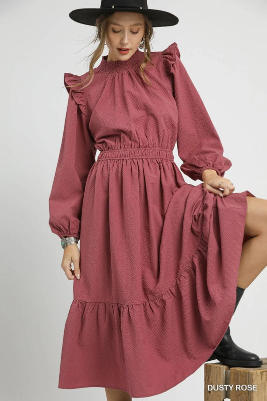 Dusty rose textured midi dress with ruffle shoulders and long sleeves.