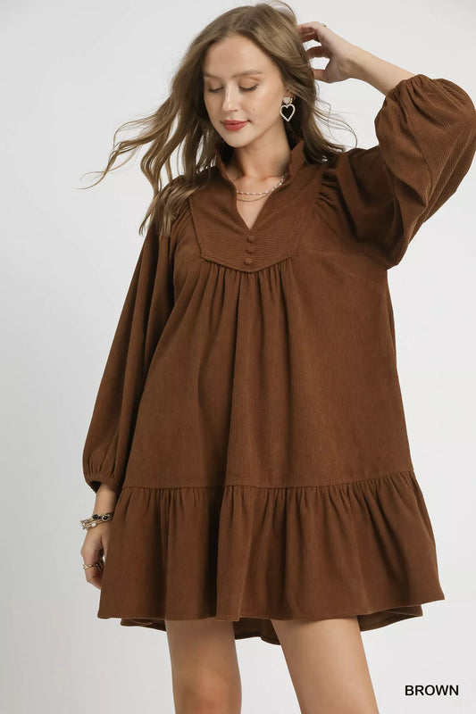 Woman modeling brown corduroy tiered babydoll dress with V-neck and puffed sleeves.