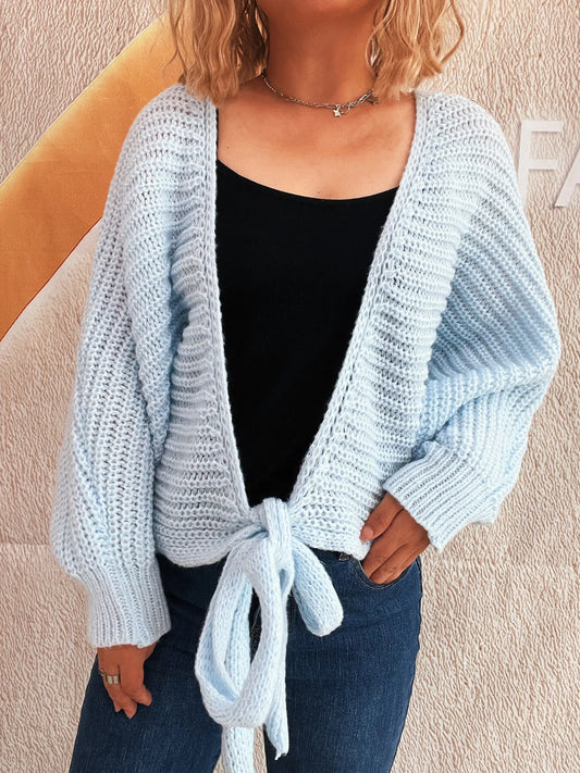 Light blue long-sleeve cardigan with tie front, worn open over black top.