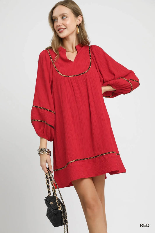 Woman modeling red textured babydoll dress with leopard trim and puff sleeves.