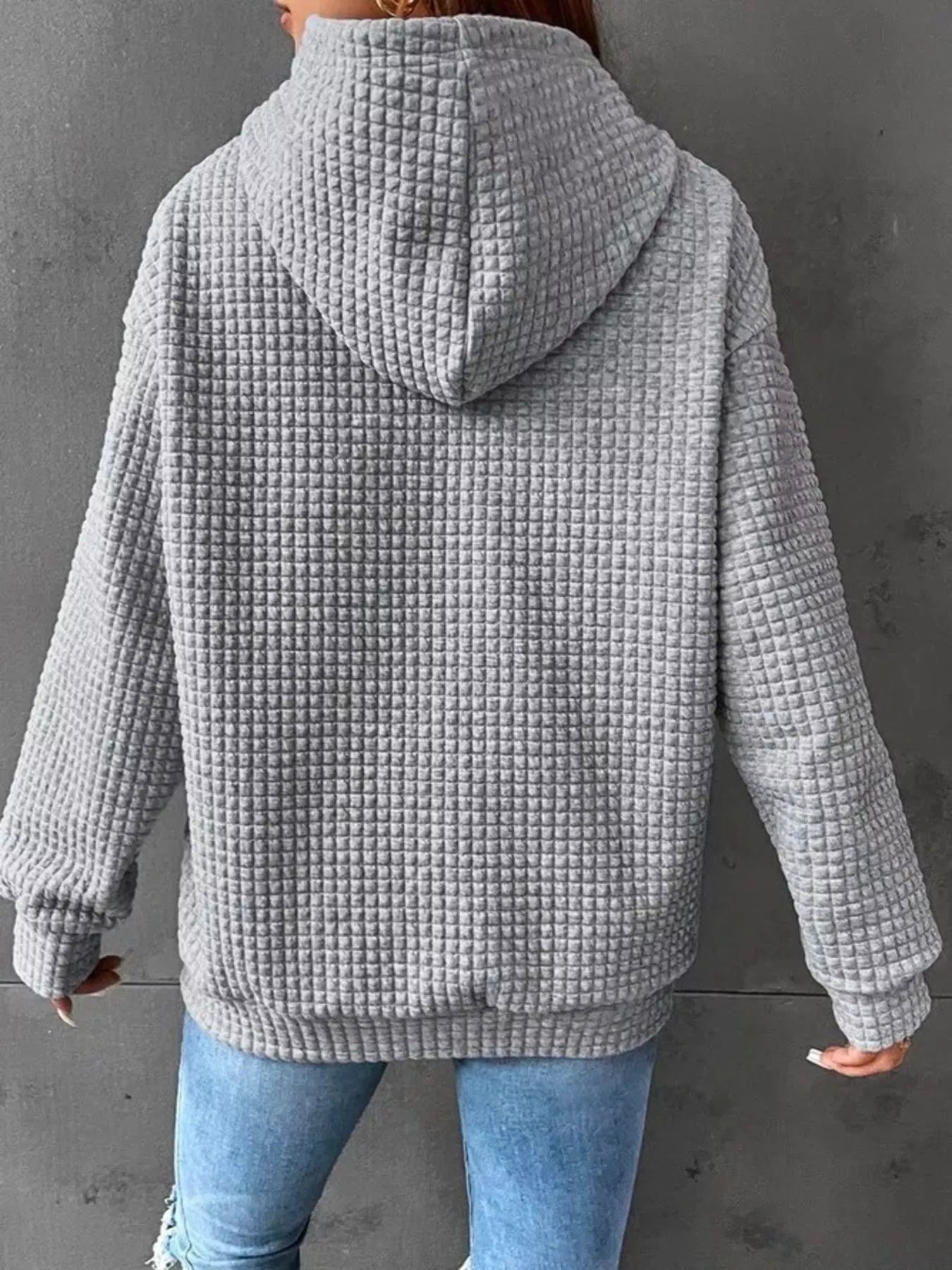 Gray waffle knit hoodie with drawstring hood and kangaroo pocket, worn by a model from behind.