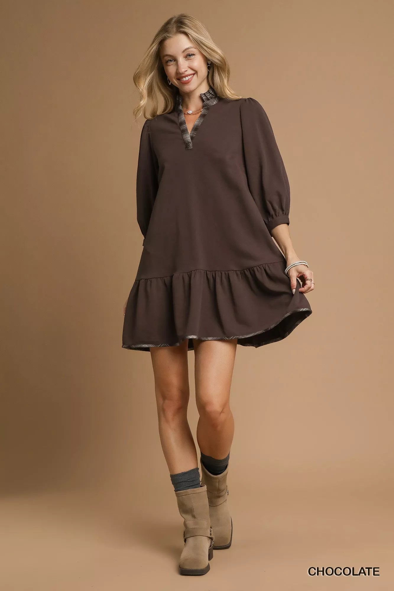 Woman modeling brown French terry ruffle hem dress with plaid trim and suede boots.