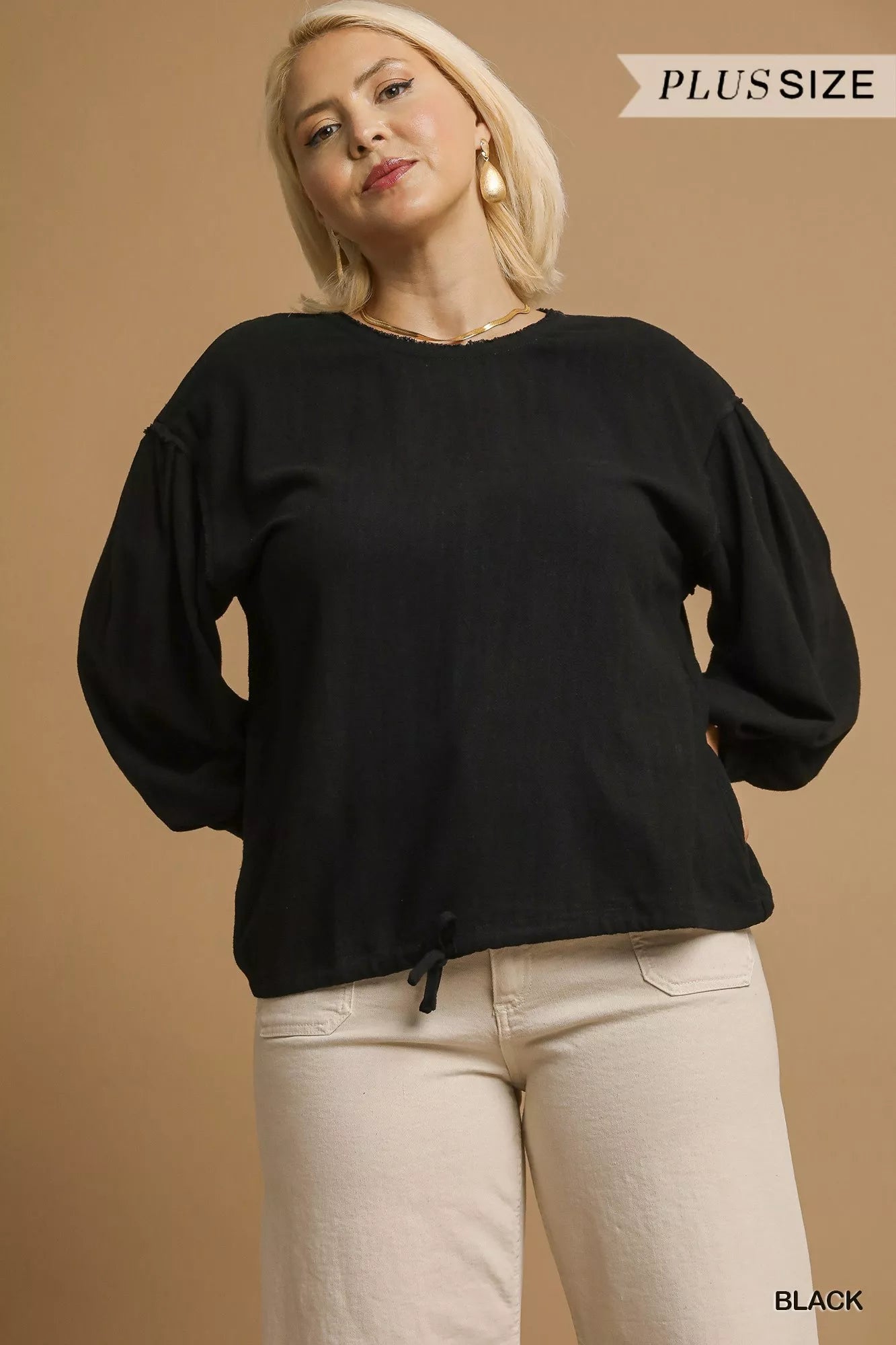 Plus-size black linen long-sleeve drawstring top on a model with beige pants.
