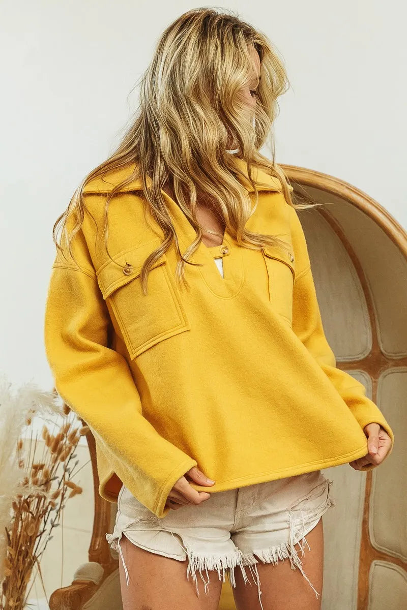 Mustard fleece collared sweatshirt with flap pockets, modeled on a woman.