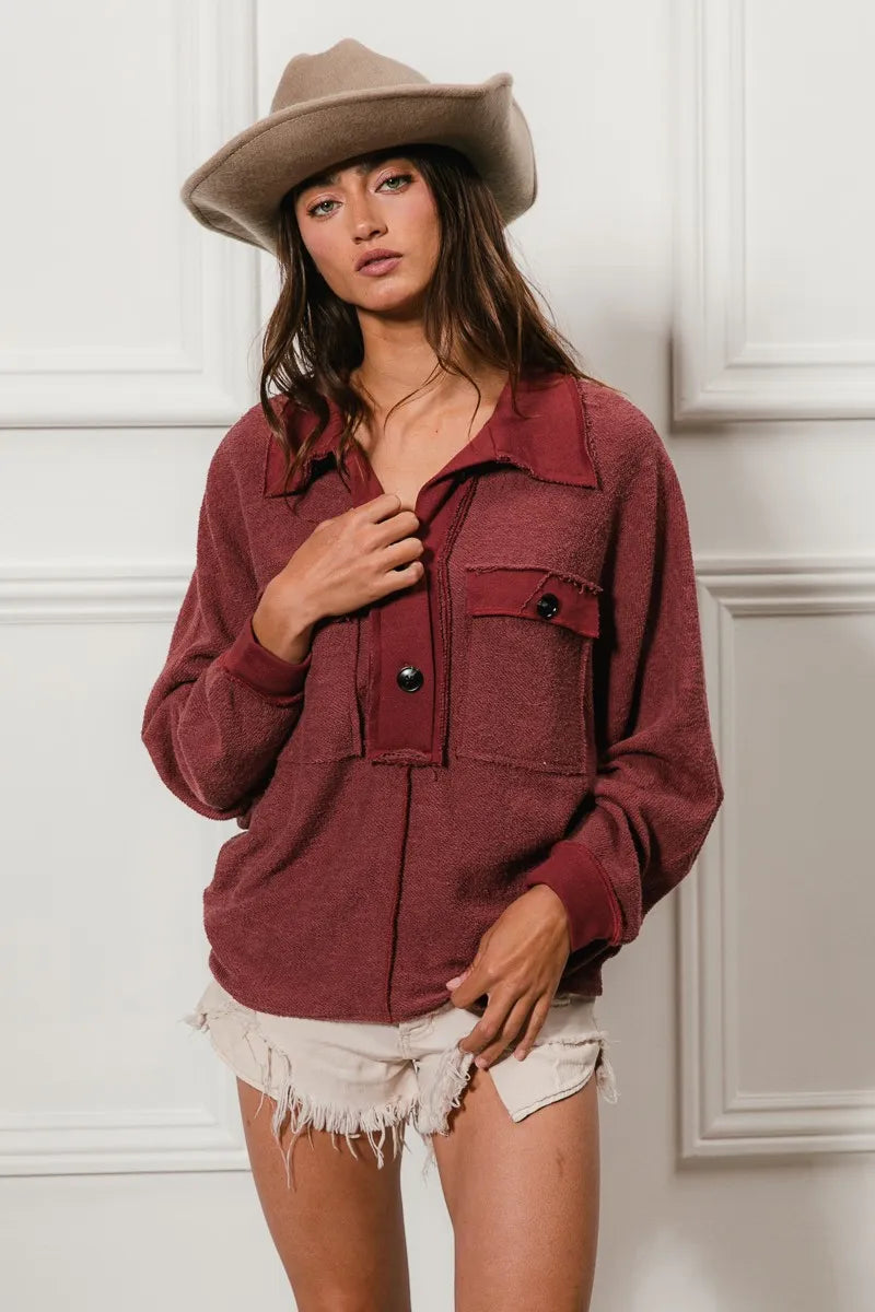 Oversized maroon French terry collared top with buttons and pockets, modeled on a woman.