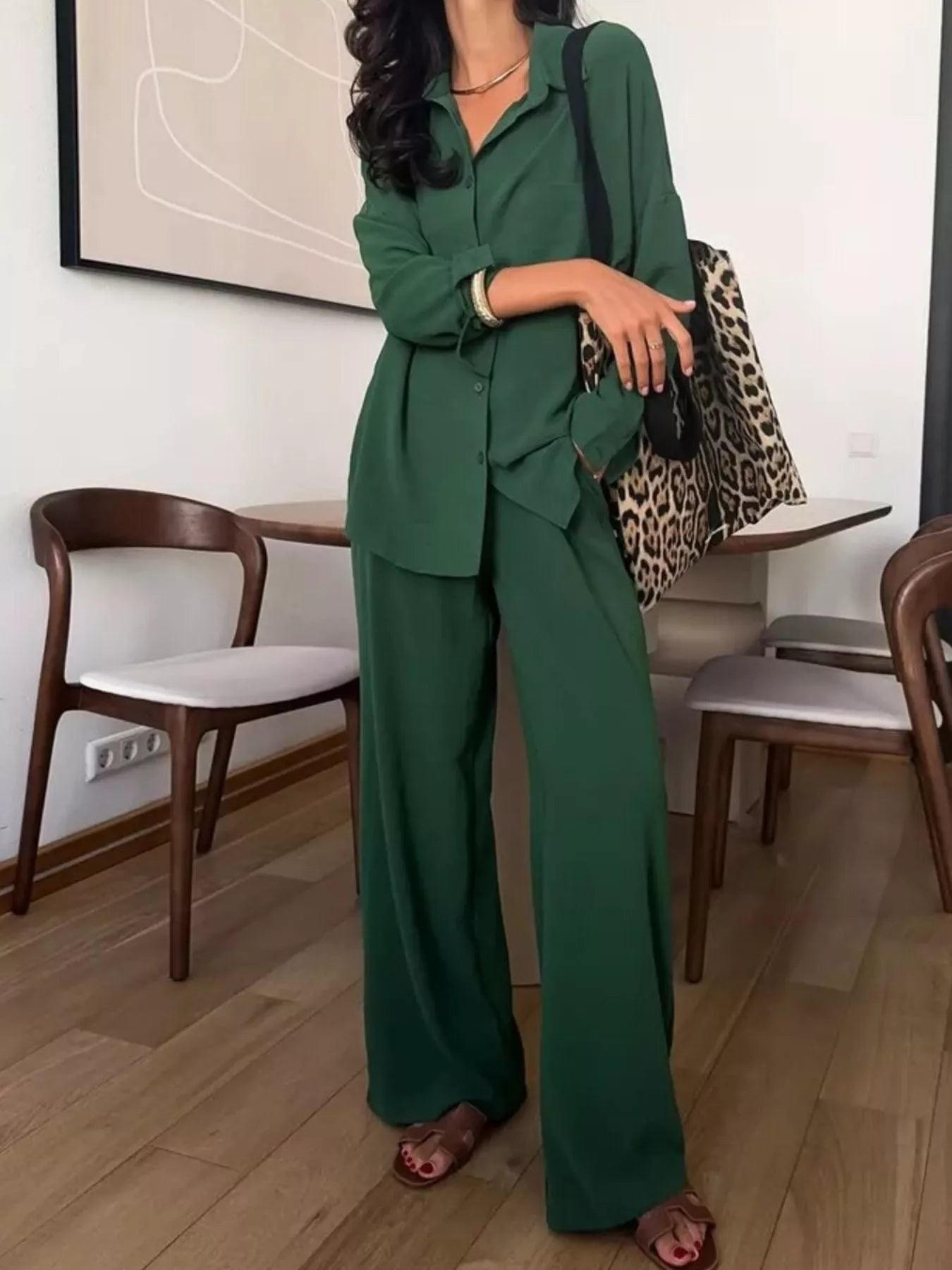 Woman wearing a green two-piece button-down shirt and wide-leg pants set with a leopard-print tote bag.