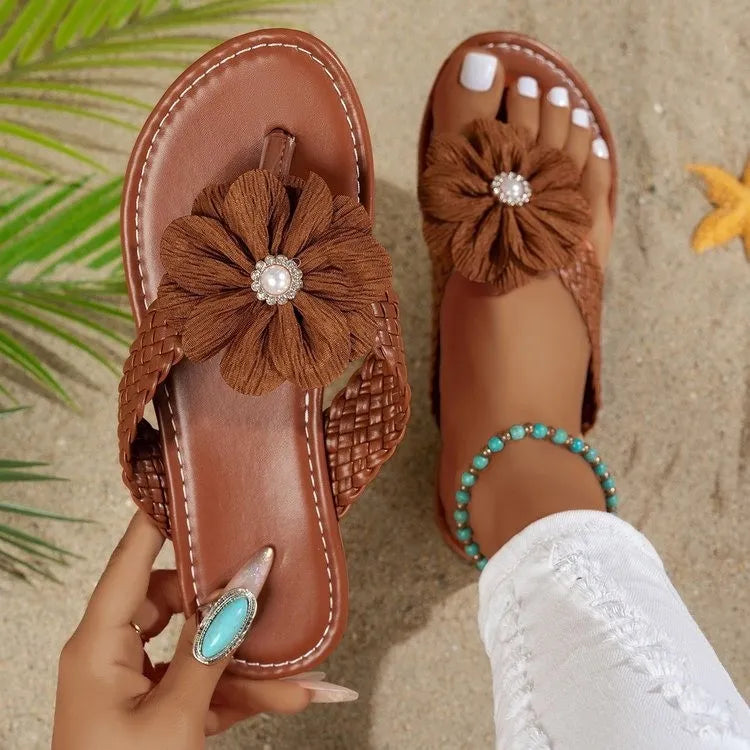 Brown leather toe-post sandals with braided straps, fabric flower accent, and turquoise bead anklet.