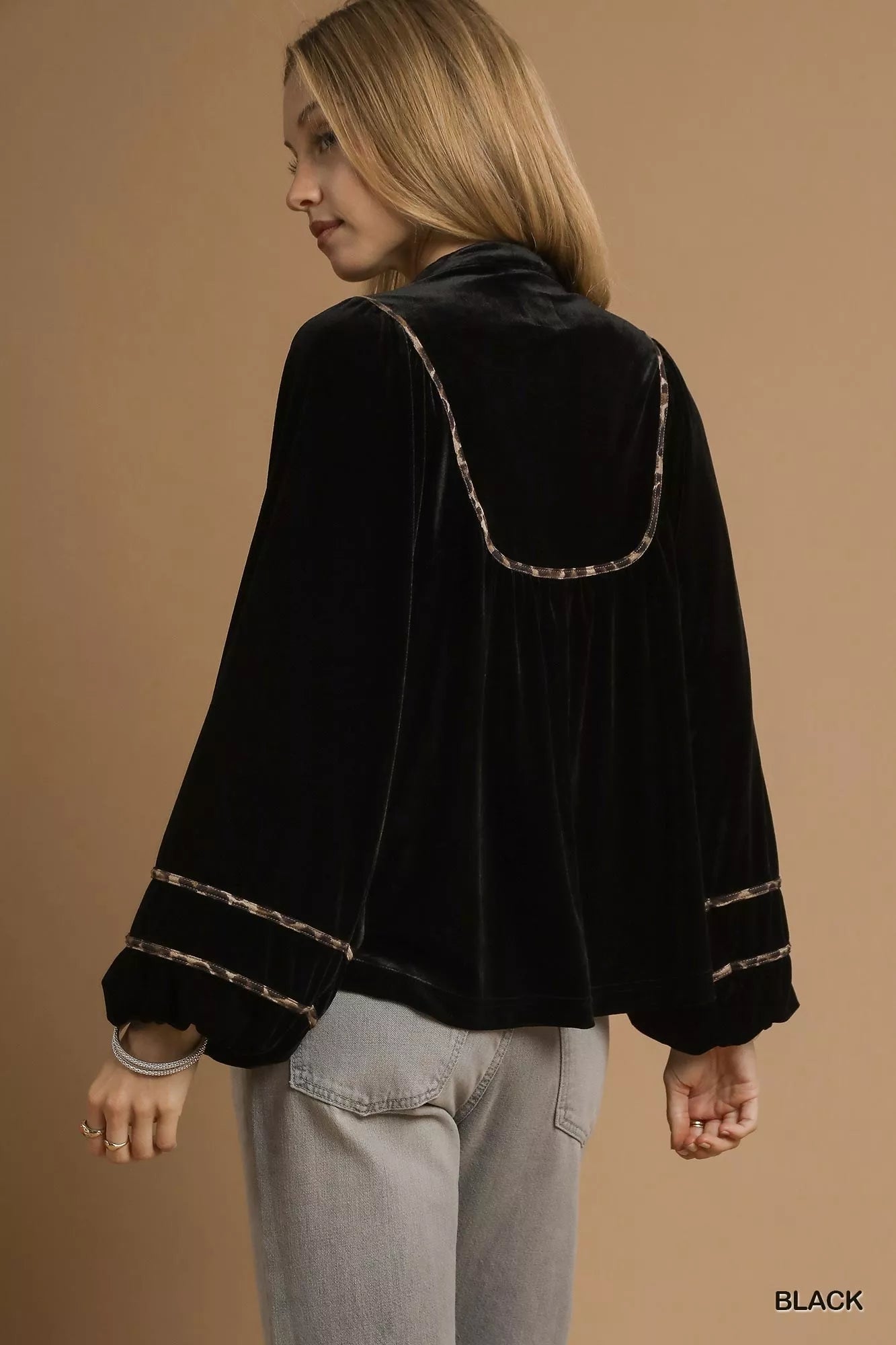 Black velvet long-sleeve blouse with contrast trim on a model.