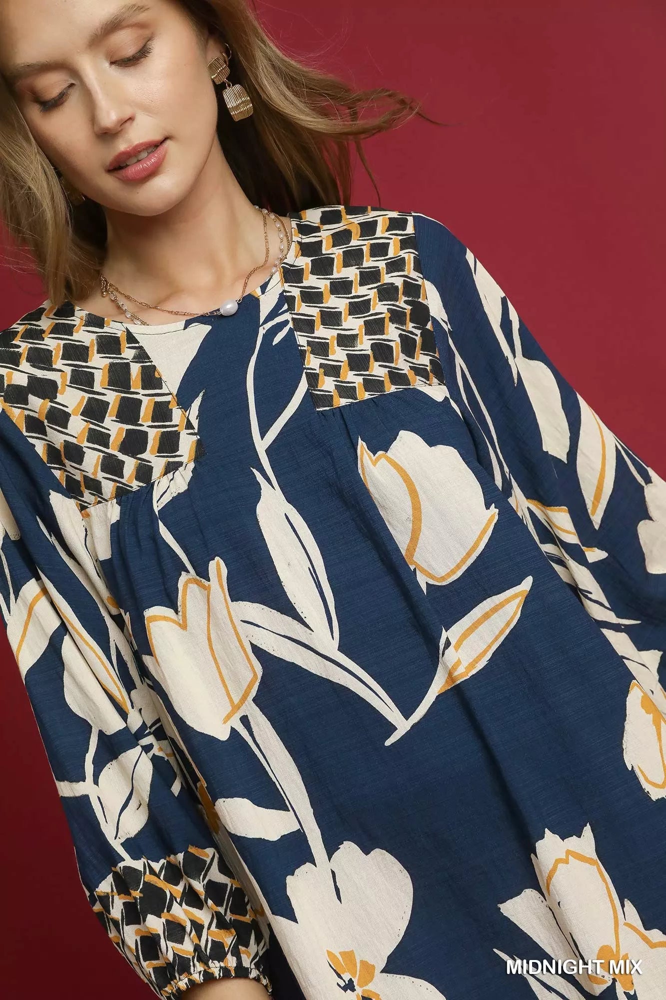 Woman modeling a navy floral high-low babydoll dress with woven trim accents.