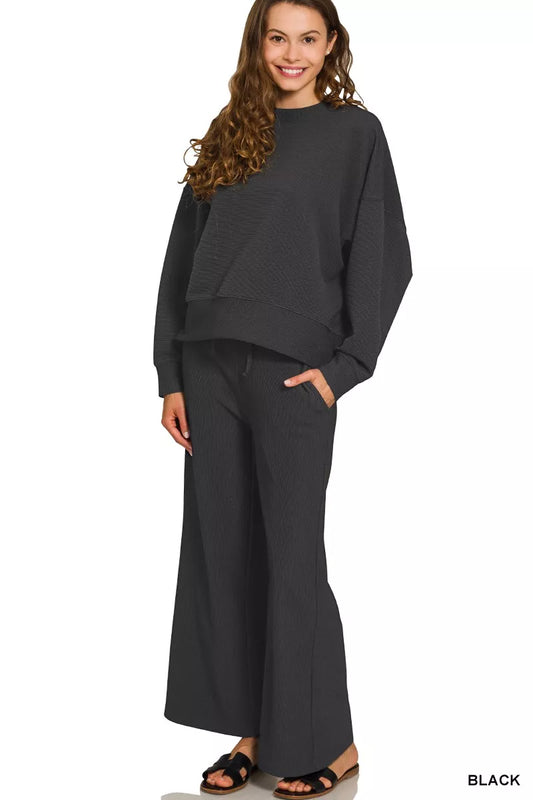 Woman modeling a black ribbed round neck pullover and drawstring pants set.