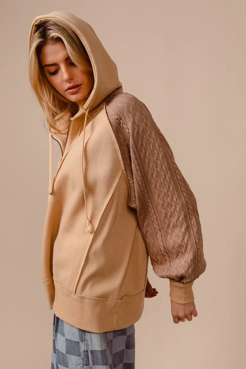 BiBi half zip French terry hoodie in beige with knit sleeves, modeled on a woman.