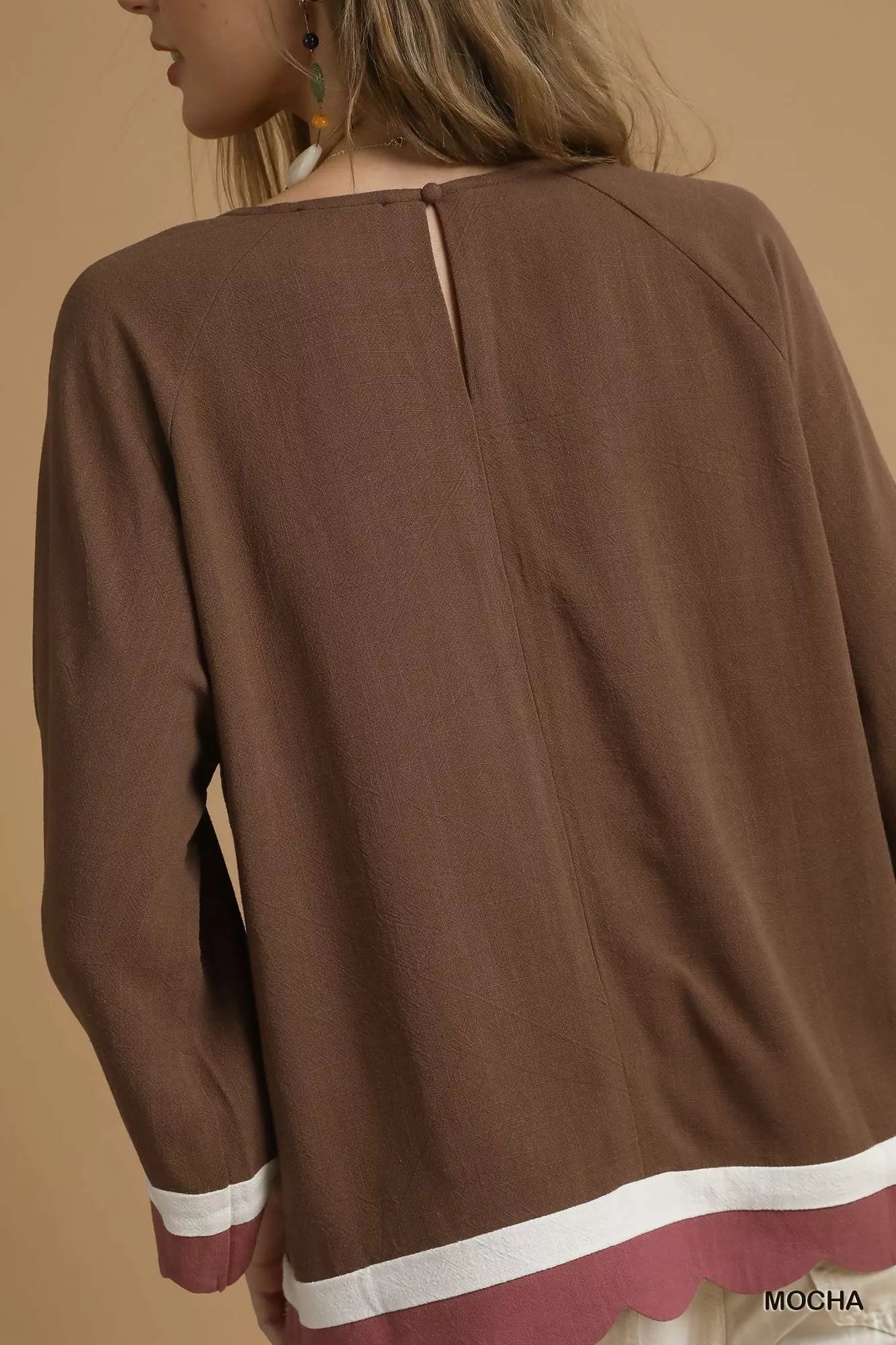 Rear view of brown Umgee linen blend top with scalloped hem and white trim.
