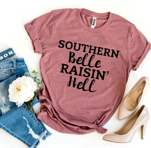 Pink Bella Canvas T-shirt with "Southern Belle Raisin' Hell" text, styled with jeans and heels.