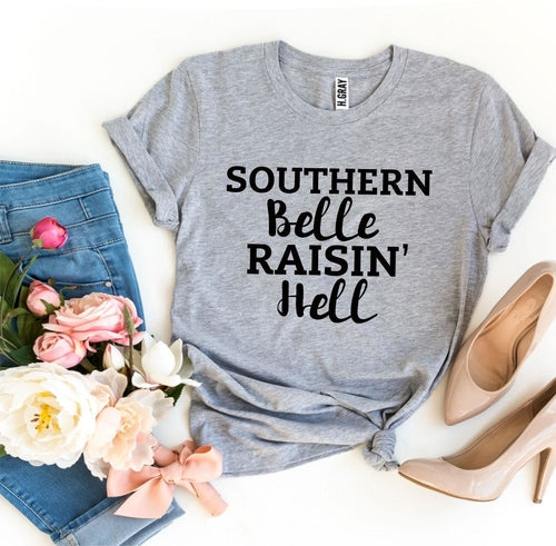 Gray Bella Canvas t-shirt with "Southern Belle Raisin' Hell" text, styled with jeans, pink roses, and nude heels.