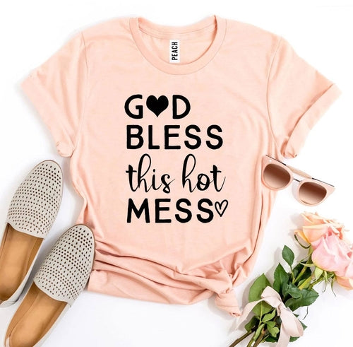 Pink Bella Canvas cotton T-shirt with "God Bless this Hot Mess" text, styled with sunglasses and rose.