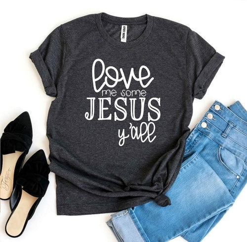 Gray Bella Canvas cotton T-shirt with "Love Me Some Jesus Y'all" text, styled with rolled sleeves, paired with jeans and black heels.
