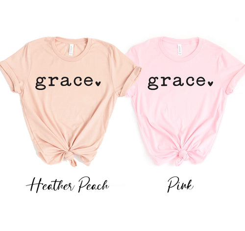 Two unisex Grace t-shirts in feather peach and pink, made of soft cotton.