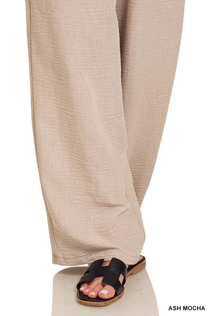 Wide-leg pants in ash mocha with woven crepe fabric and black H-strap sandals.