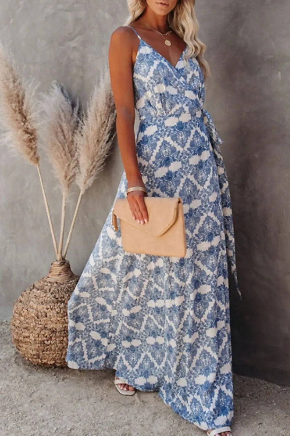 Blue ikat printed tied maxi cami dress on a model holding a beige clutch.